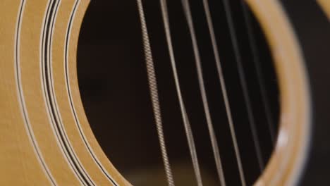 Plucking-the-string-of-an-acoustic-guitar-in-slow-motion-over-the-Sound-hole