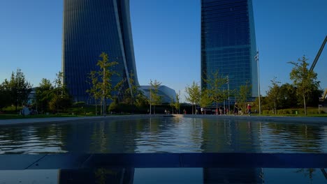 The-three-towers-of-the-City-Life-Lombardy-district-in-Milan,-Italy,-are-reflected-in-the-fountain-below-them