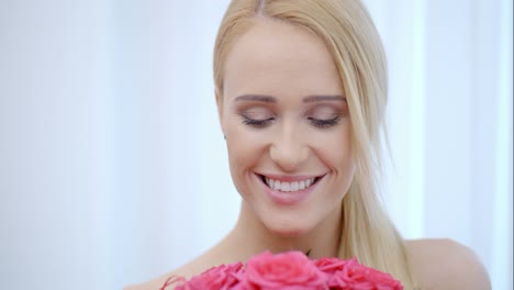 Smiling-Blond-Woman-Smelling-Pink-Roses