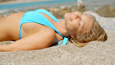 Blond-Woman-Suntanning-on-Beach-with-Eyes-Closed