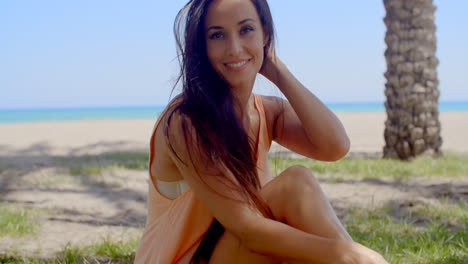 Attractive-Woman-Sitting-at-Grassy-Beach-Ground
