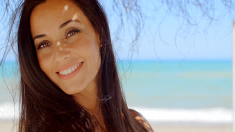 Woman-Under-a-Beach-Umbrella-Smiling-at-Camera