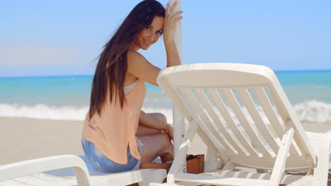 Smiling-Pretty-Woman-Sitting-on-Beach-Sun-Lounger