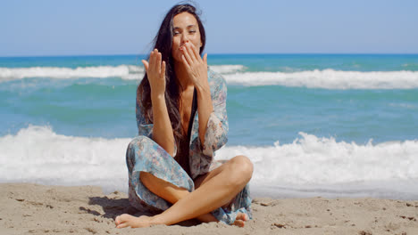 Hübsches-Mädchen-Sitzt-Auf-Strandsand-Und-Küsst-Ihre-Handfläche