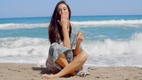 Hübsches-Mädchen-Sitzt-Auf-Strandsand-Und-Küsst-Ihre-Handfläche