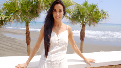 Woman-in-White-Dress-Leaning-Against-Beach-Wall