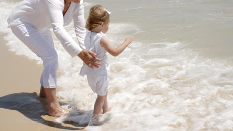 Mom-Holding-her-Girl-at-Splashing-Beach-Water