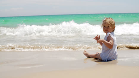 Kleines-Mädchen-Sitzt-An-Einem-Strand-In-Der-Nähe-Des-Wassers