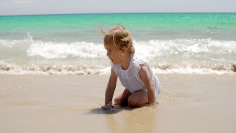 Kleines-Mädchen-Sitzt-An-Einem-Strand-In-Der-Nähe-Des-Wassers
