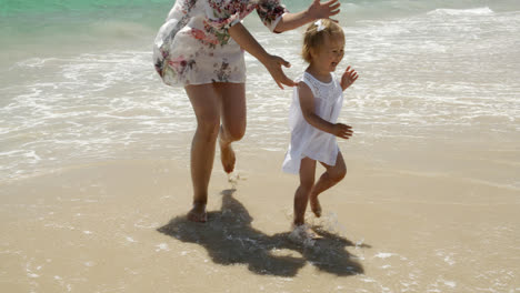 Little-girl-running-along-a-beach-with-her-mother
