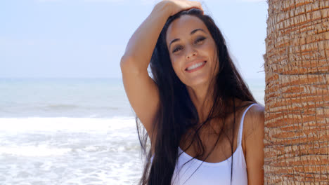 Mujer-Sonriente-En-La-Playa-Apoyada-Contra-El-árbol
