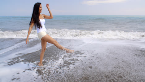 Carefree-Woman-Kicking-Up-Water-on-Tropical-Beach
