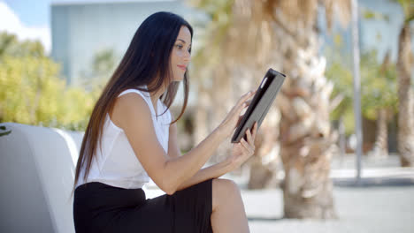 Smiling-young-woman-using-her-tablet-outdoors