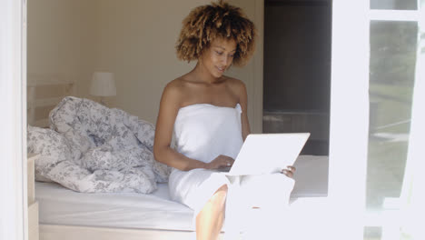 Young-Woman-Using-Laptop-On-Bed