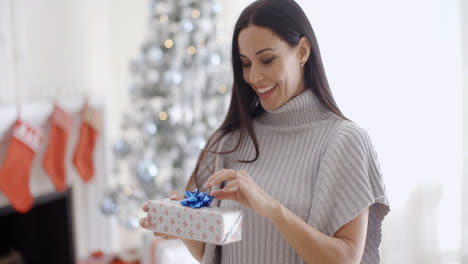 Smiling-young-woman-opening-a-Christmas-present