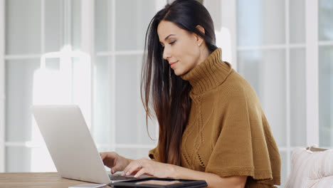 Attractive-woman-sitting-typing-on-a-laptop