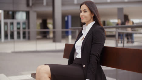 Optimistic-business-woman-sitting-outdoors