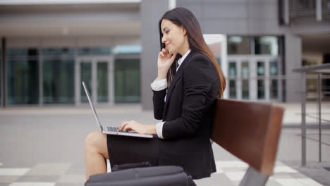 Woman-looking-over-with-laptop-on-bench