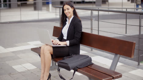 Woman-looking-over-with-laptop-on-bench
