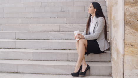 Grinning-woman-on-stairs-drinking-coffee