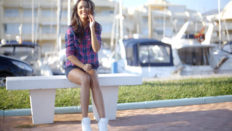 Young-Woman-Sitting-On-Bench-In-Harbor