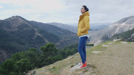 Woman-in-yellow-coat-near-mountain-valley