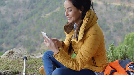 Smiling-female-hiker-using-her-phone