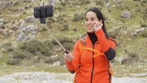 Smiling-young-backpacker-using-a-selfie-stick
