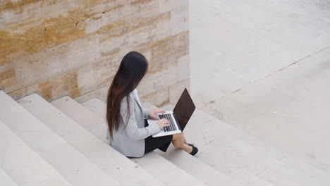 High-angle-view-of-woman-on-laptop-on-stairs