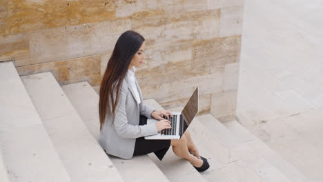 Side-view-of-woman-using-laptop-on-stairs