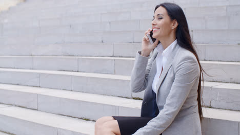 Laughing-woman-sitting-on-steps-with-phone