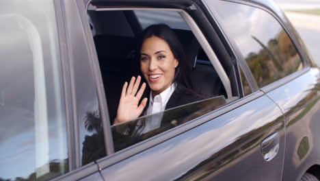 Cute-business-woman-sitting-in-car-waving-hand