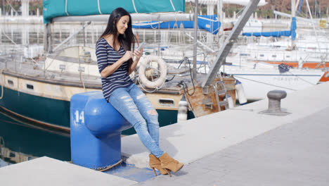 Trendy-young-woman-relaxing-at-a-marine-harbour