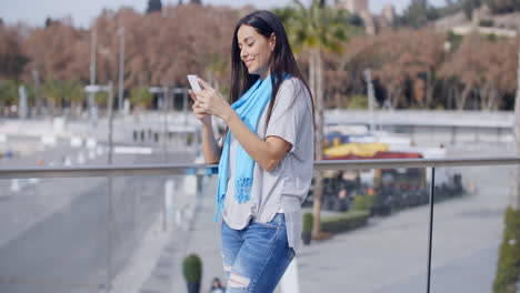 Grinning-woman-using-phone-on-overpass