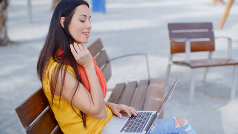 Stylish-young-woman-outdoors-working-on-a-laptop