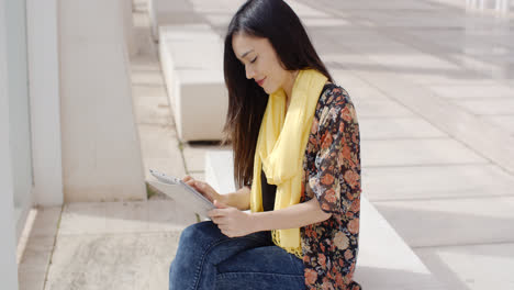 Young-woman-sitting-reading-her-tablet