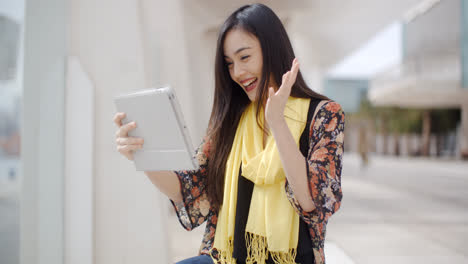 Excited-woman-waving-at-her-tablet-computer