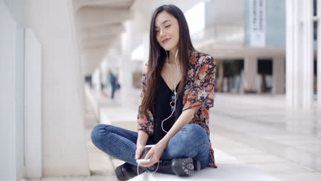 Trendy-young-woman-listening-to-music-in-town