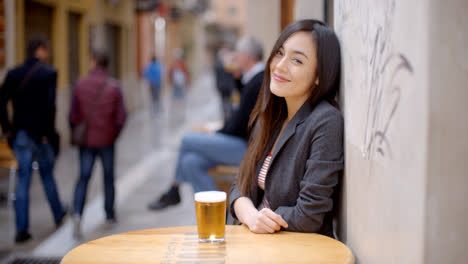 Friendly-young-woman-sitting-enjoying-a-beer