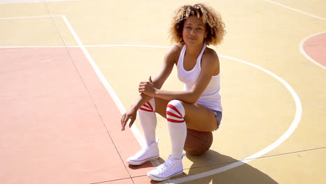 Attractive-female-athlete-sits-on-basketball
