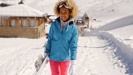 Smiling-pretty-young-woman-carrying-a-snowboard