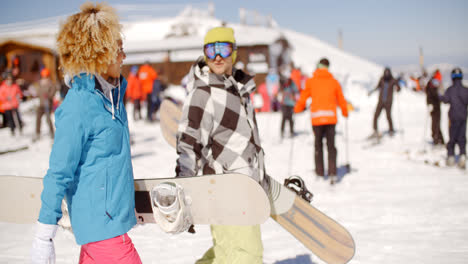 Young-couple-carrying-their-snowboards-at-a-resort