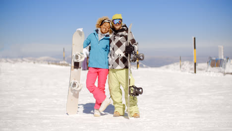 Happy-young-couple-posing-with-their-snowboards
