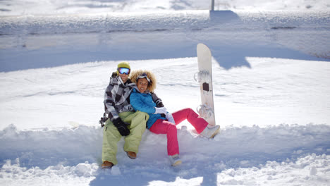 Happy-young-couple-sitting-on-a-deep-shelf-of-snow