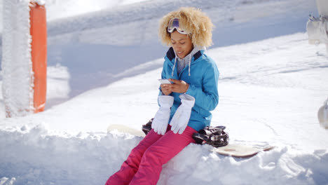 Woman-sitting-on-snowbank-texting