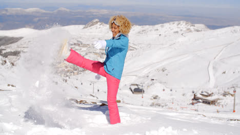 Cute-woman-in-skiing-clothes-kicking-snow