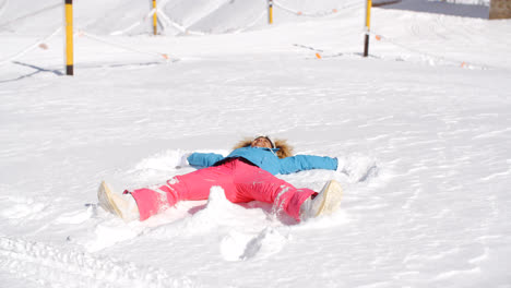Young-woman-making-a-snow-angel-in-white-snow