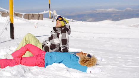 Couple-resting-on-hill-after-skiing