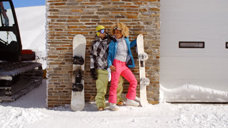 Cute-couple-leaning-against-ski-resort-garage