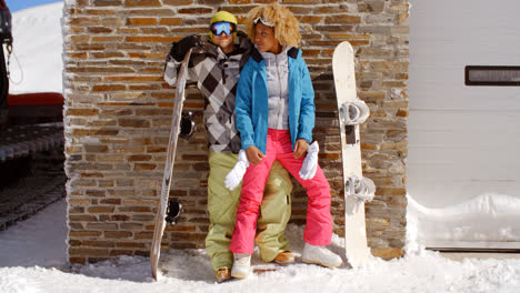 Close-couple-posing-with-snowboards-against-garage